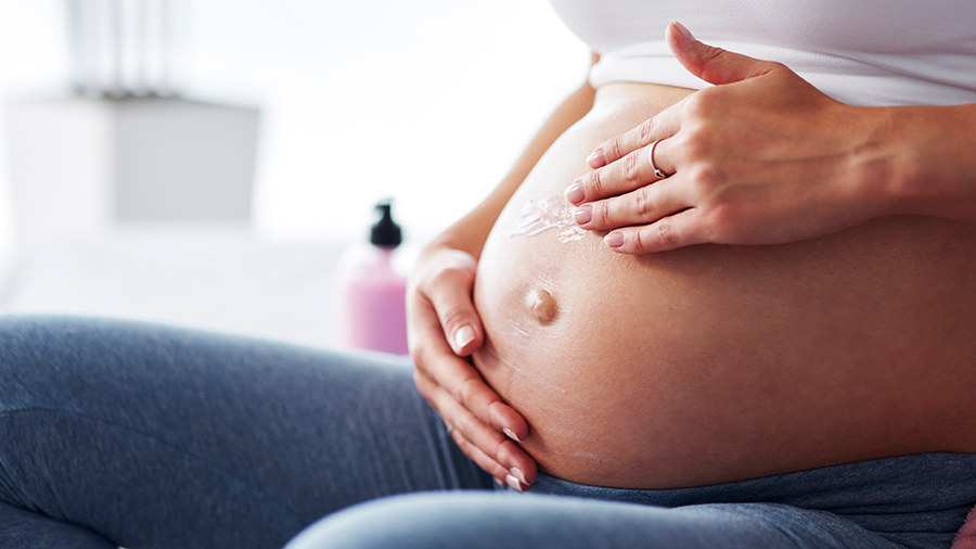 Femme enceinte s'applicant une crême anti-vergetures sur le ventre